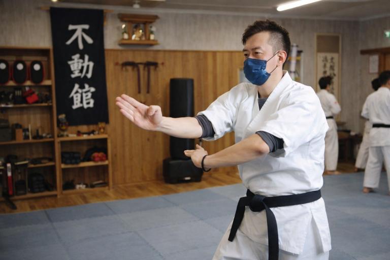 空手道場内で尾鱗の構えを取る不動館の実戦護身構え
