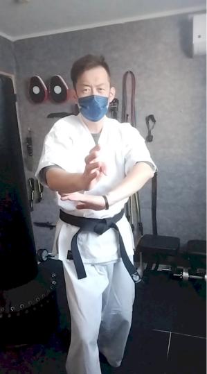 空手道場内で尾鱗の構えを取る不動館の実戦護身構え
