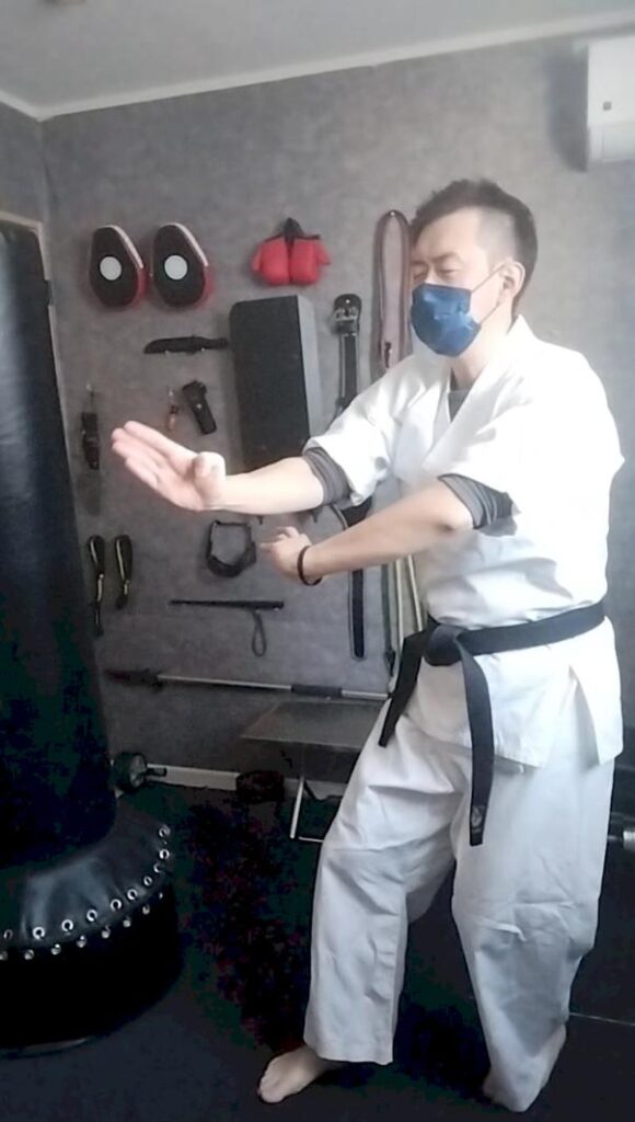 空手道場内で尾鱗の構えを取る不動館の実戦護身構え
